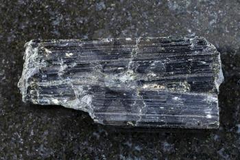 macro shooting of natural mineral rock specimen - rough aegirine crystals on dark granite background from Khibiny Mountains, Kola Peninsula, Russia