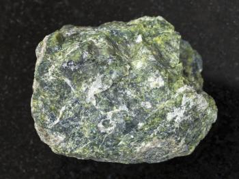 macro shooting of natural mineral rock specimen - raw serpentine stone on dark granite background