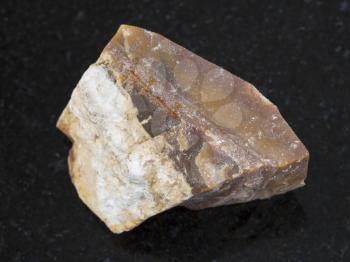 macro shooting of natural mineral rock specimen - raw brown Flint stone on dark granite background