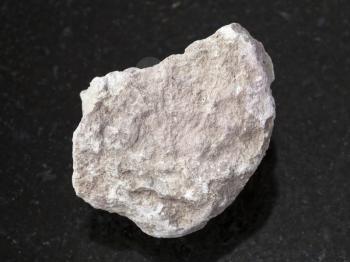 macro shooting of natural mineral rock specimen - rough marl stone on dark granite background