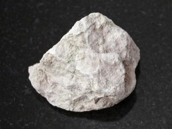 macro shooting of natural mineral rock specimen - raw marl stone on dark granite background