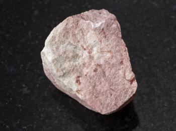 macro shooting of natural mineral rock specimen - rough calcareous sandstone stone on dark granite background