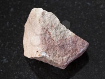 macro shooting of natural mineral rock specimen - raw calcareous sandstone stone on dark granite background