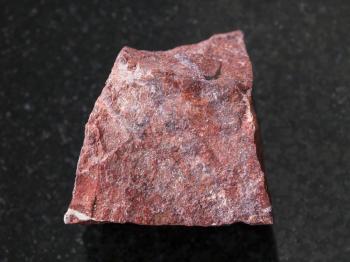 macro shooting of natural mineral rock specimen - rough red jasper stone on dark granite background