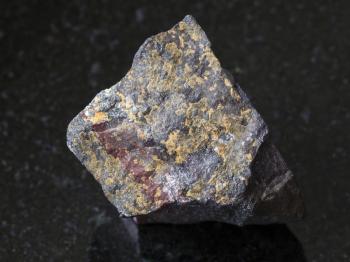macro shooting of natural mineral rock specimen - jaspilite (ferruginous quartzite) stone on dark granite background