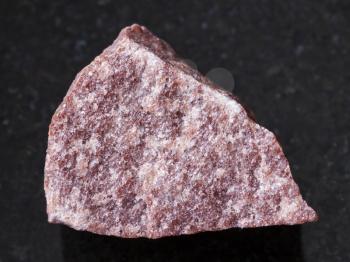 macro shooting of natural mineral rock specimen - rough pink Quartzite stone on dark granite background