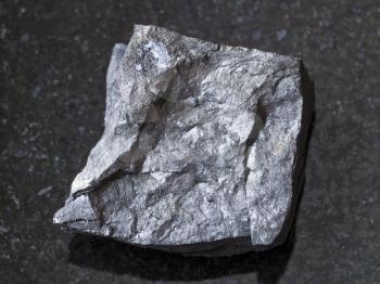 macro shooting of natural mineral rock specimen - raw carbonaceous shale stone on dark granite background