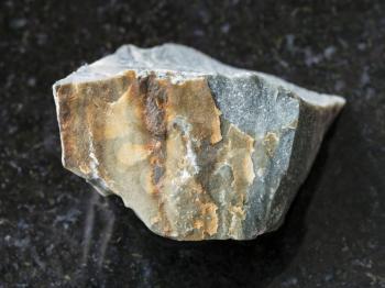 macro shooting of natural mineral rock specimen - rough Hornfels stone on dark granite background