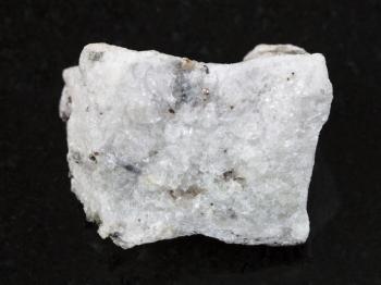 macro shooting of natural mineral rock specimen - rough carbonatite stone on dark granite background