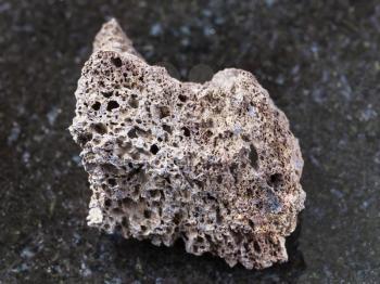 macro shooting of natural mineral rock specimen - rough Pumice of basic composition stone on dark granite background