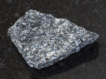 macro shooting of natural mineral rock specimen - rough nepheline syenite stone on dark granite background