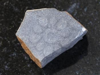 macro shooting of natural mineral rock specimen - rough hyalobasalt (tachylite) stone on dark granite background