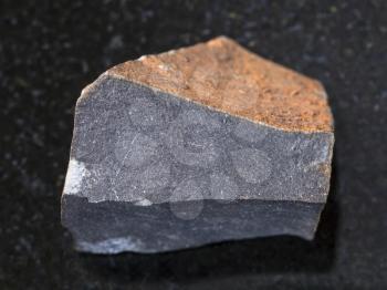 macro shooting of natural mineral rock specimen - raw hyalobasalt (tachylite) stone on dark granite background