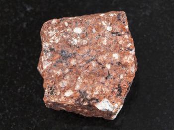 macro shooting of natural mineral rock specimen - raw Dacite stone on dark granite background