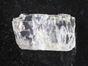 macro shooting of natural mineral rock specimen - raw crystal of Petalite gemstone on dark granite background from Araguaia mine, Brazil