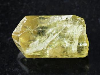 macro shooting of natural mineral rock specimen - rough crystal of yellow apatite gemstone on dark granite background from Mexico