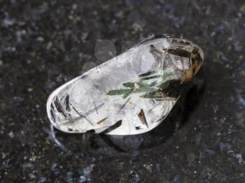 macro shooting of natural mineral rock specimen - polished quartz gemstone with Tourmaline crystals (tourmalinated quartz) on dark granite background