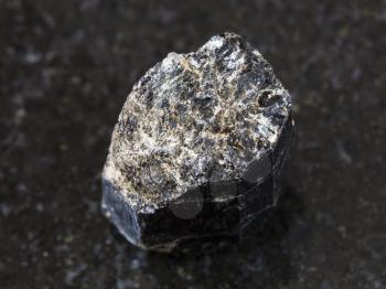 macro shooting of natural mineral rock specimen - broken crystal of Schorl (black tourmaline) gemstone on dark granite background from Madagascar