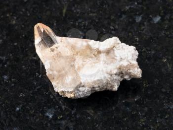 macro shooting of natural mineral rock specimen - raw crystal of topaz gemstone on dark granite background from Brazil