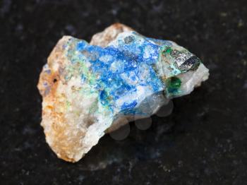 macro shooting of natural mineral rock specimen - tennantite crystal, green Tyrolite and blue Azurite on raw quartz stone on dark granite background from Ural Mountains, Russia
