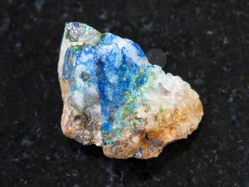 macro shooting of natural mineral rock specimen - tennantite crystal, green Tyrolite and blue Azurite on rough quartz stone on dark granite background from Ural Mountains, Russia