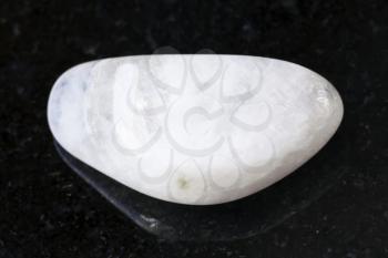 macro shooting of natural mineral rock specimen - polished white moonstone (adularia) gemstone on dark granite background