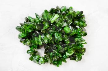 string of beads from natural chrome diopside crystals on gray concrete background