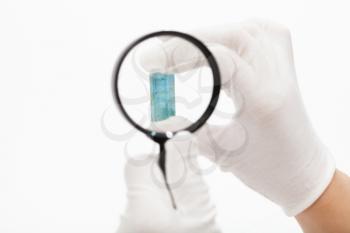 master inspects aquamarine crystal with magnifier on white background