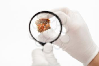 master inspects spessartine garnets with magnifier on white background