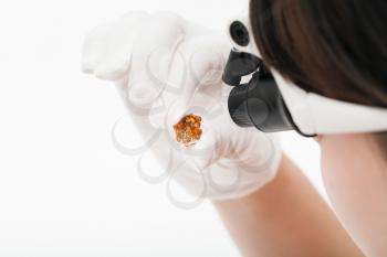 master in head-mounted lens checks spessartine crystals on whie background