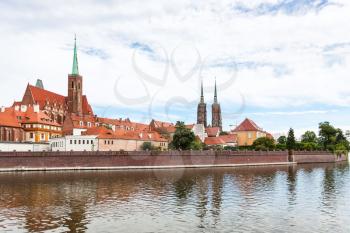 travel to Poland - old Collegiate Church of the Holy Cross and St Bartholomew and towers of Cathedral of St John the Baptist in Ostrow Tumski district in Wroclaw city from Oder River