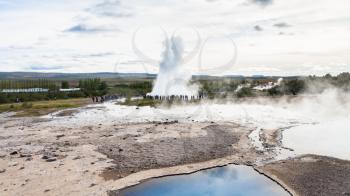 travel to Iceland - tourists near Strokkur geyser eruption and pool of Geysir in Haukadalur area in autumn