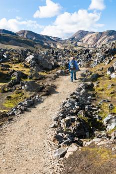 travel to Iceland - tourist on trail at Laugahraun volcanic lava field in Landmannalaugar area of Fjallabak Nature Reserve in Highlands region of Iceland in september