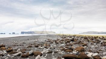 travel to Iceland - surface of Reynisfjara Beach and view of Dyrholaey cape in Iceland, near Vik I Myrdal village on Atlantic South Coast in Katla Geopark in autumn