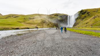 travel to Iceland - people walk to Skogafoss waterfall in Katla Geopark in september