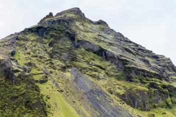 travel to Iceland - slope of volcanic mountains near Skogafoss waterfall in Katla Geopark on Icelandic Atlantic South Coast in september