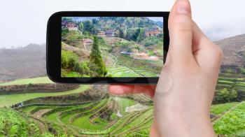 travel concept - tourist photographs Dazhai village in Longsheng (Dragon's Backbone, Longji) Rice Terraces county in China in spring on smartphone