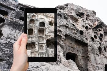 travel concept - tourist photographs carved rocks of West Hill of Chinese Buddhist monument Longmen Grottoes on tablet