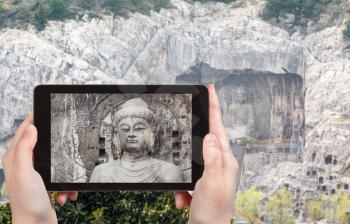 travel concept - tourist photographs The Big Vairocana statue on West Hill of Chinese Buddhist monument Longmen Grottoes (Longmen Caves) from the east bank of the Yi River in spring season on tablet
