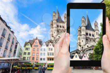 travel concept - tourist photographs Fischmarkt square and Great St Martin Church in Cologne city in Germany on tablet