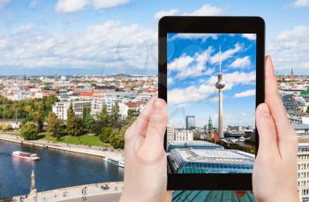 travel concept - tourist photographs Berlin cityscape with TV Tower and Spree river on tablet