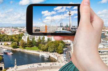 travel concept - tourist photographs Berlin city with TV Tower and Spree river on smartphone
