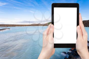 travel concept - tourist photographs Blue Lagoon Geothermal lake in Grindavik lava field outside spa resort in Iceland in autumn evening on tablet with cut out screen for advertising logo view of