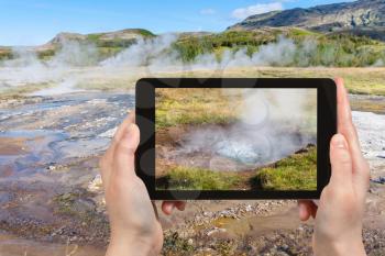 travel concept - tourist photographs earth surface in Haukadalur hot spring area in Iceland in september on tablet