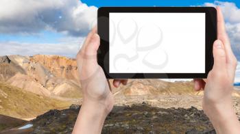 travel concept - tourist photographs Laugahraun volcanic lava field in Landmannalaugar area of Fjallabak Nature Reserve in Highlands region of Iceland on tablet with cut out screen