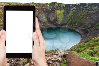 travel concept - tourist photographs Kerid lake in volcanic crater in Iceland in autumn on tablet with cut out screen for advertising logo