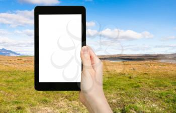 travel concept - tourist photographs icelandic landscape along Biskupstungnabraut road near Gullfoss waterfall in Iceland in autumn on tablet with cut out screen for advertising logo
