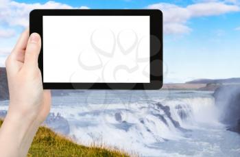 travel concept - tourist photographs Gullfoss waterfall on Olfusa river in Iceland in autumn on tablet with cut out screen for advertising logo