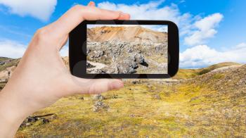 travel concept - tourist photographs Laugahraun volcanic lava field in Landmannalaugar area of Fjallabak Nature Reserve in Highlands region in Iceland in september on smartphone