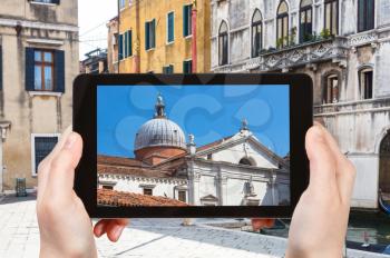 travel concept - tourist photographs church Chiesa Santa Maria Formosa from canal in Venice city in Italy in spring on tablet